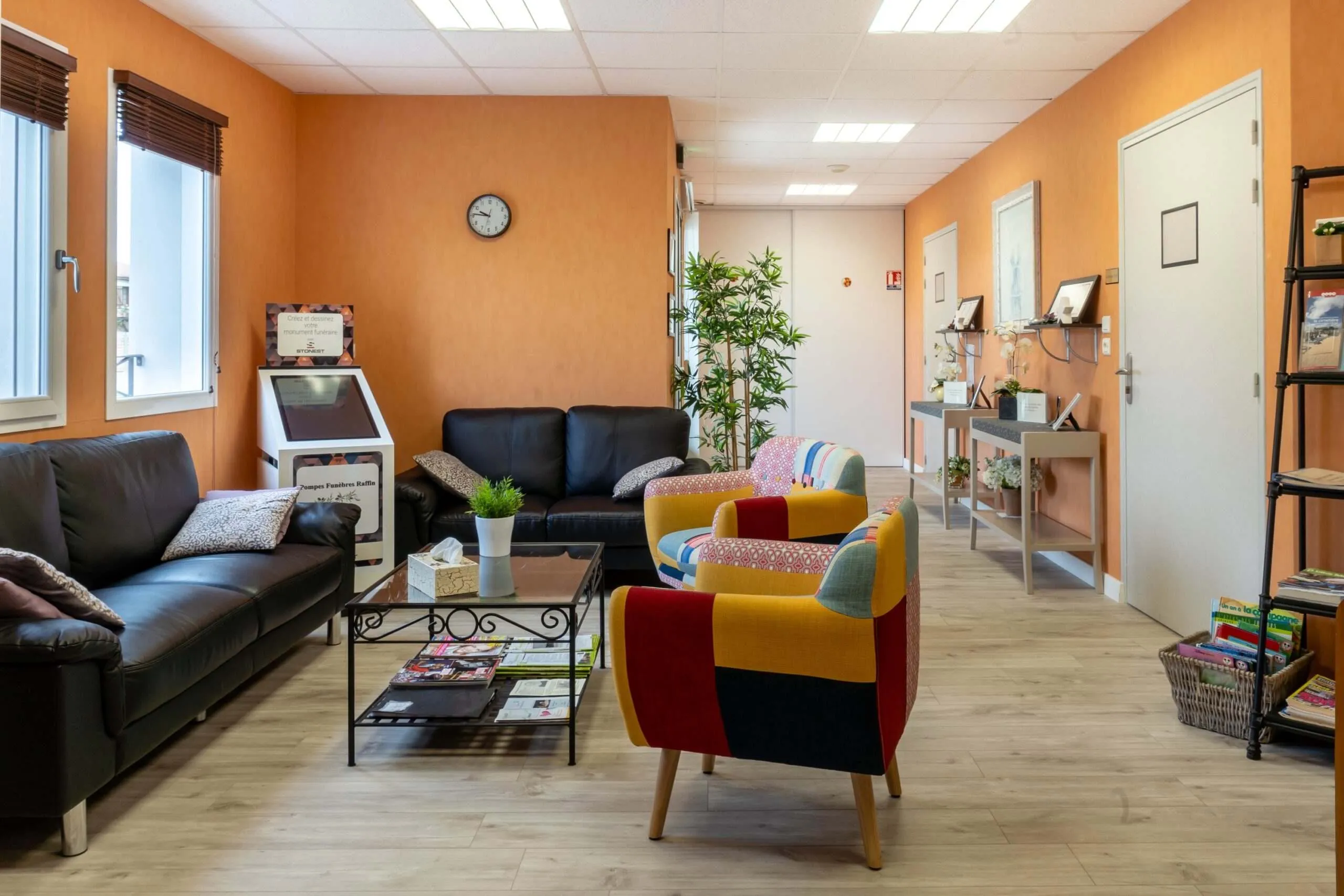Espace d'attente d'un funérarium doté de fauteuils colorés, canapés et borne interactive