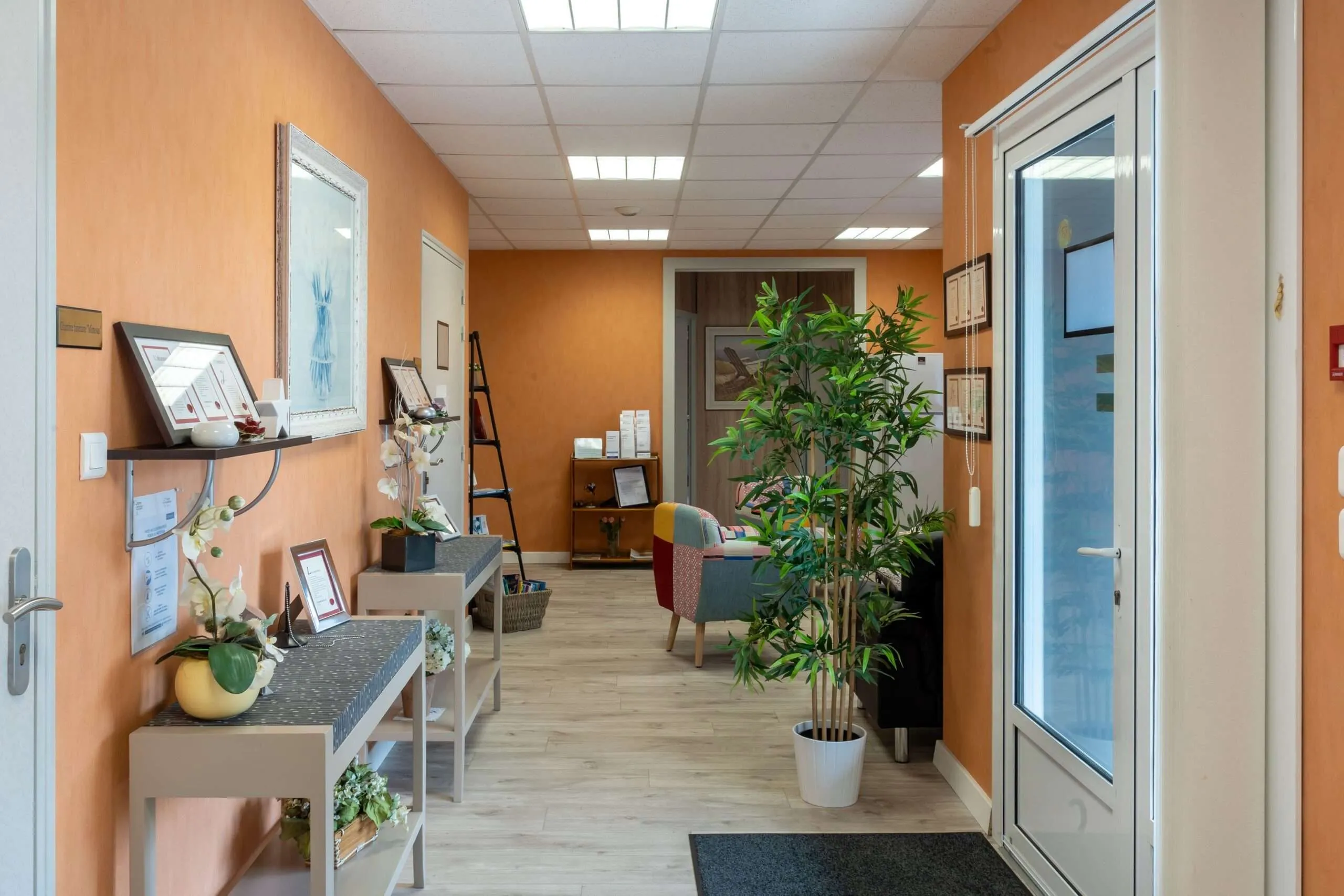 Couloir d'accueil d'un funérarium aux tons orangés avec consoles décoratives et plante