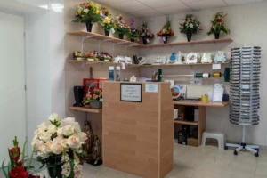 Comptoir d'accueil du magasin d'articles funéraires bordé de fleurs et de plaques