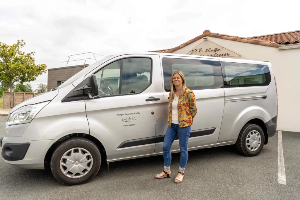Conseillère funéraire posant à côté du véhicule de transport des Pompes Funèbres Raffin