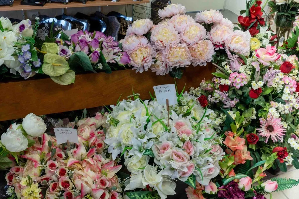 Composition étagée de bouquets de fleurs artificielles pour hommage funéraire